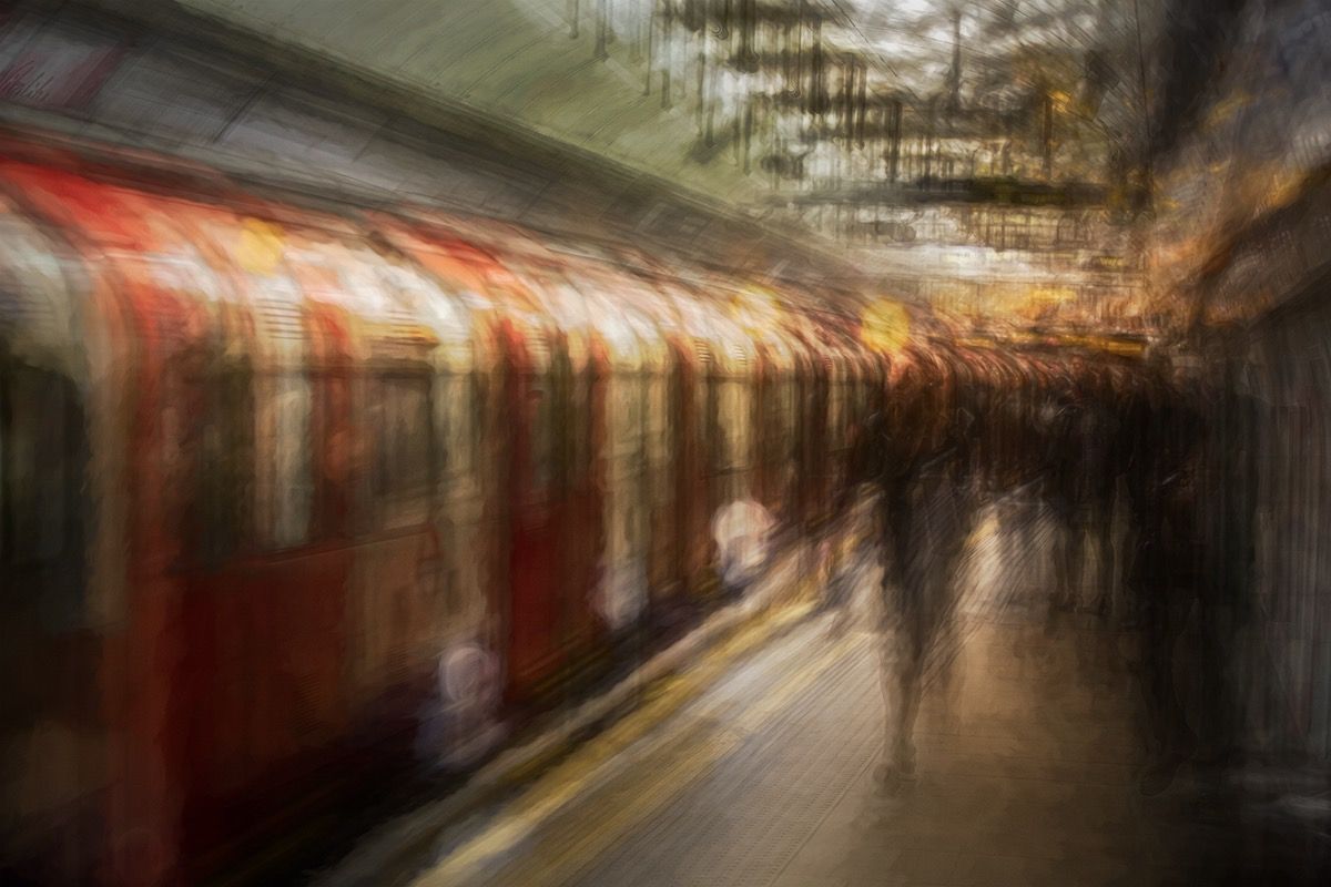 A London Underground train at a crowded platform, blurred with movement